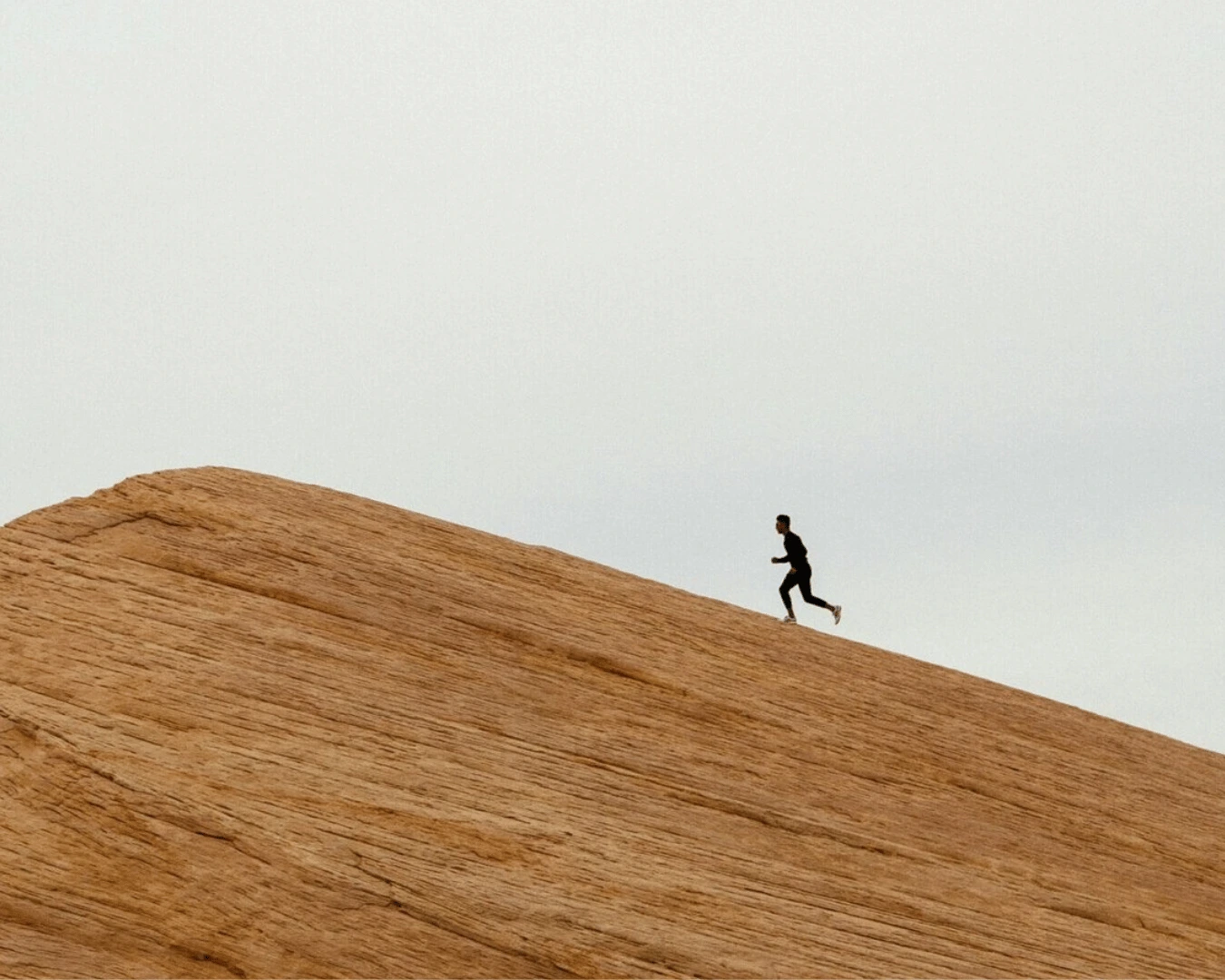 Runner silhouetted on a sand dune ridge