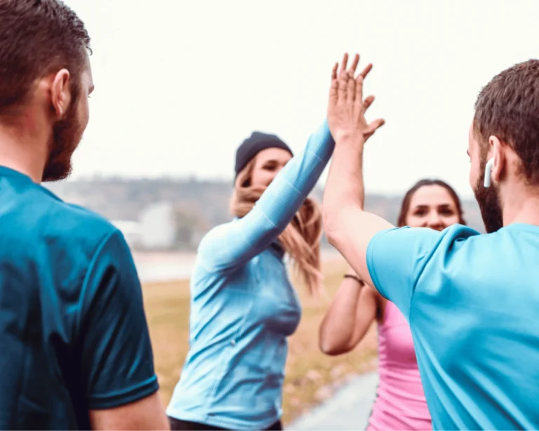 Group of runners high-fiving during outdoor training