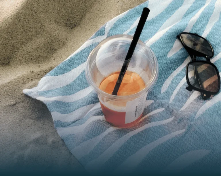 Iced drink and sunglasses on a beach towel